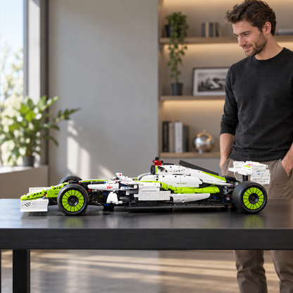 Pessoa adulta ao lado de um carro de blocos verde e branco apoiado sobre uma mesa, em vista lateral.